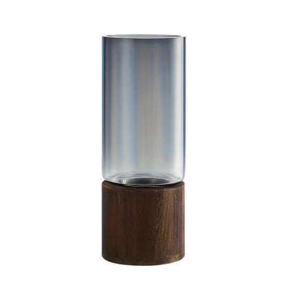 glass vase with wooden base holding pink roses on a table.
clear glass cylinder vase with dark wood base for home decor.
