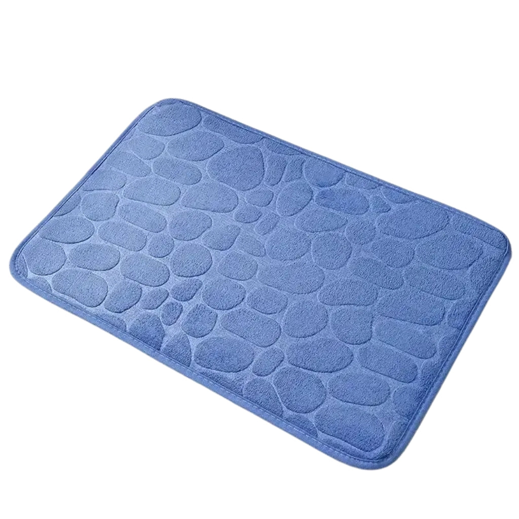 Pebble pattern bath rug shown with white slippers on tile floor