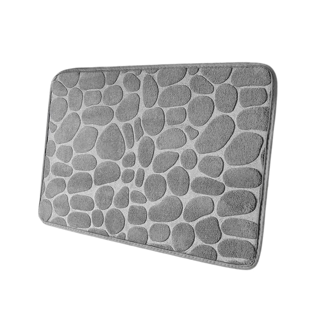 Pebble pattern bath rug shown with white slippers on tile floor