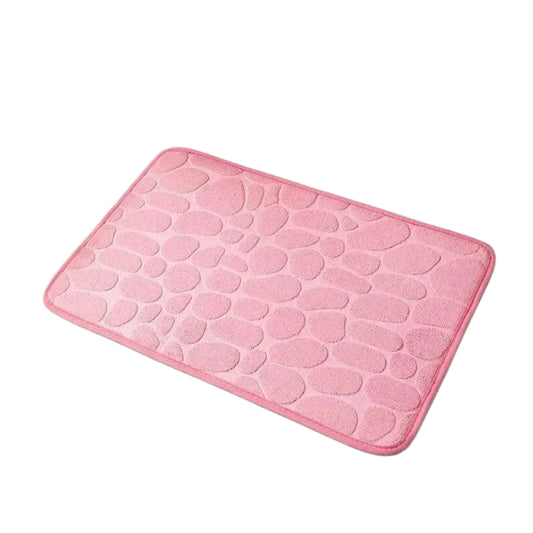 Pink bathroom mat with pebble texture placed beside a bathtub