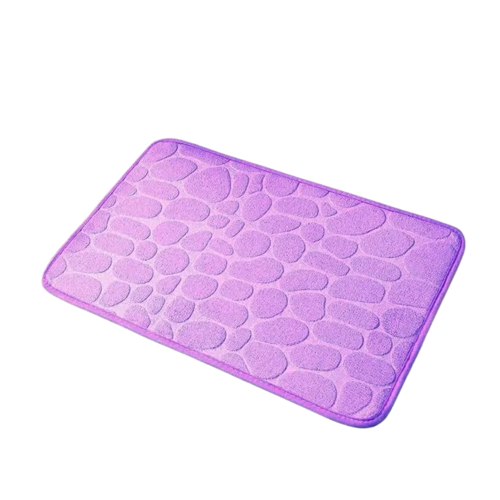 Pebble pattern bath rug shown with white slippers on tile floor